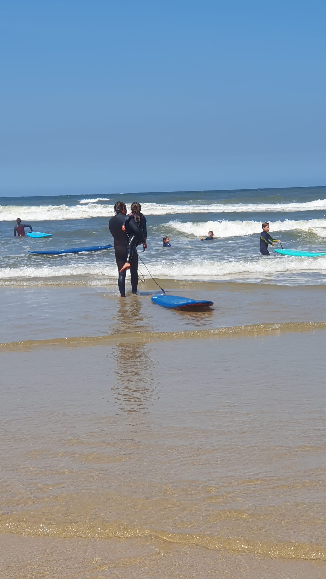 Instructor with children in shallow water — kids surf lessons Praia da Aguda, near Porto